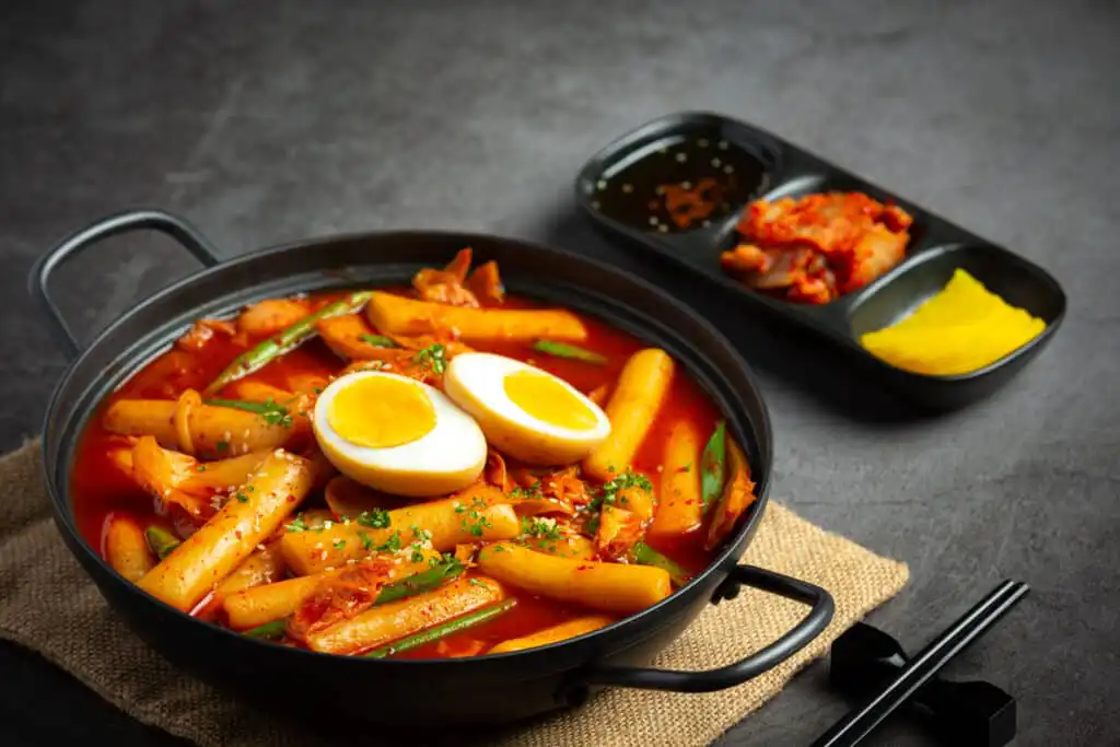 A bowl of spicy Tteokbokki with rice cakes, vegetables, and fish cakes.