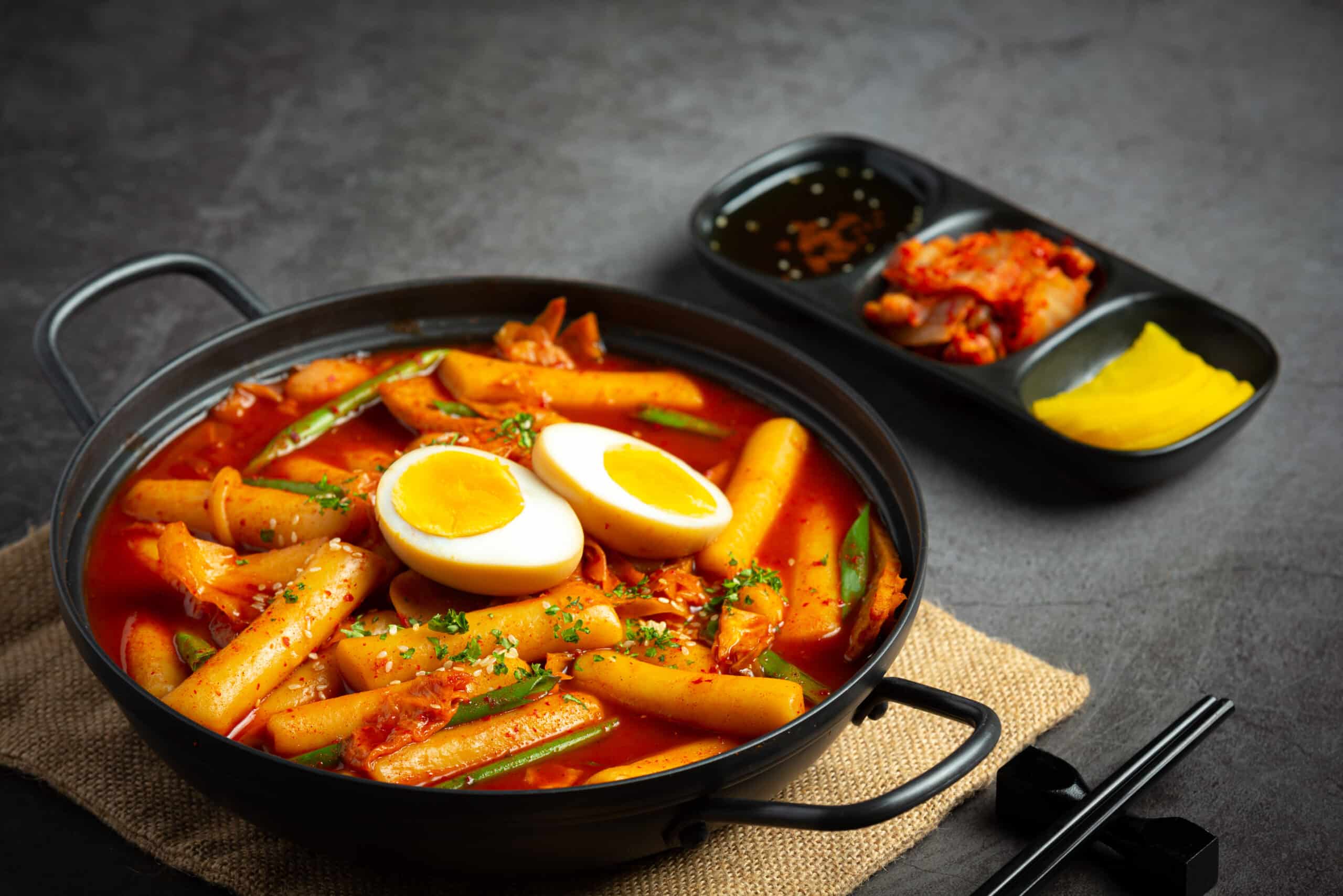 A bowl of spicy Tteokbokki with rice cakes, vegetables, and fish cakes.