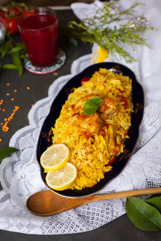 A hearty plate of chicken and yellow rice garnished with fresh herbs.
