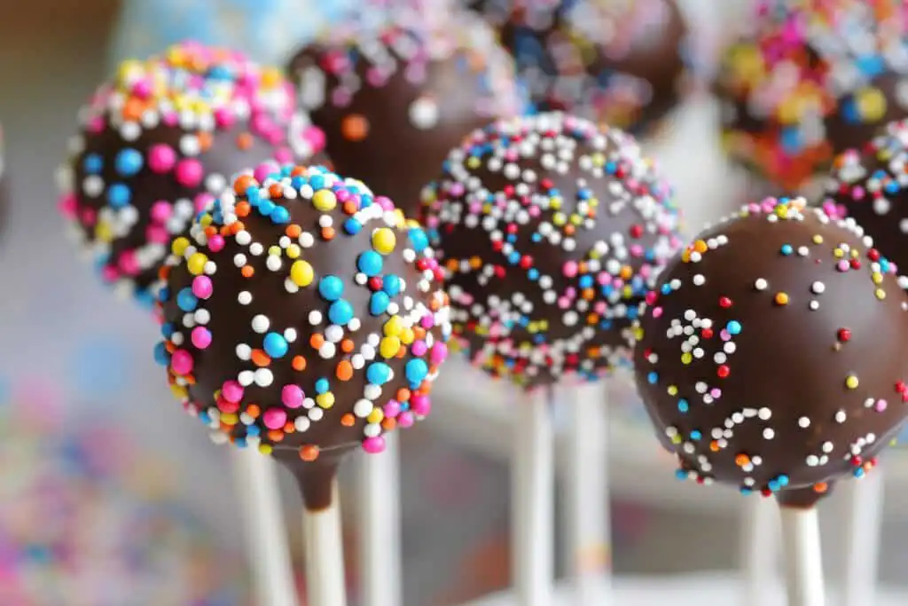Colorful cake pops decorated with sprinkles and displayed on a stand