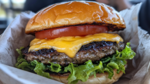 A delicious burger topped with aioli, lettuce, tomato, and cheese, captured in vibrant detail on an iPhone 15 Pro.